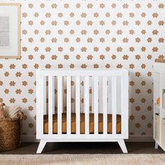 a white crib in front of a wall with brown flowered designs on it