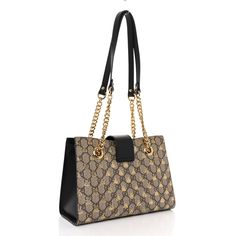 This is an authentic GUCCI GG Supreme Monogram Bees Small Padlock Tote in Beige, Oro, and Black. This chic shoulder bag is crafted of Gucci GG monogram coated canvas with a gold bee print and black leather trim. The handbag features gold chain handles with leather shoulder pads and a crossover flap with a gold padlock. The top is open to a beige suede interior with patch pockets. Gg Monogram, Gold Bee, Bee Print, Leather Trim, Shoulder Pads, Leather Trims, Gold Chain, Crossover, Patch Pocket