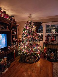 a brightly lit christmas tree is in the corner of a living room with wooden floors