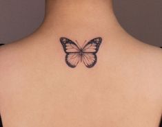 a butterfly tattoo on the back of a woman's neck