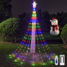 a lighted christmas tree with a snowman in the background and remotes on the ground