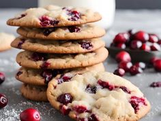 a stack of cookies with cranberry toppings next to a glass of milk