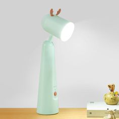 a desk lamp sitting on top of a wooden table next to a small figurine