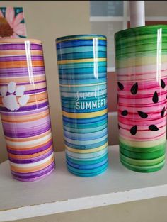 three different colored tumbles sitting on top of a shelf next to each other,