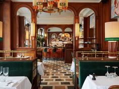 the interior of a restaurant with tables, chairs and chandeliers hanging from the ceiling