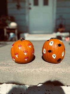 two pumpkins with faces painted to look like cats