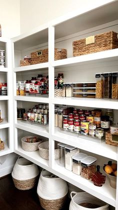 an organized pantry with white shelves and baskets on the bottom shelf, full of food