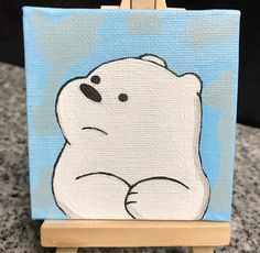 a painting of a polar bear sitting on top of a wooden easel with blue sky in the background