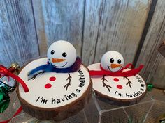 two snowmen sitting on top of wooden slices