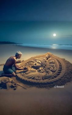 a man sitting on top of a sandy beach next to an intricate sand carving sculpture