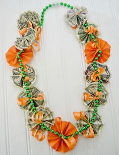 a necklace made out of dollar bills and orange bowknots with green beads