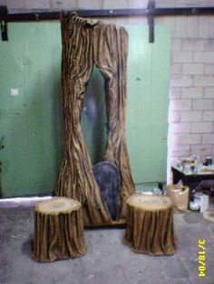 two tree stumps sitting next to each other in front of a green door with a mirror