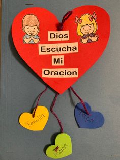 a red heart with spanish words hanging from it's sides and two hearts attached to the strings