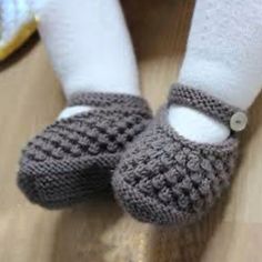 someone is wearing crocheted gray slippers with white socks and one has a button in the middle