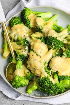 broccoli covered in gravy on a plate with a spoon