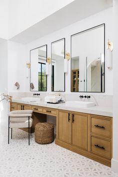 a bathroom with two sinks and three mirrors on the wall next to a stool in front of it