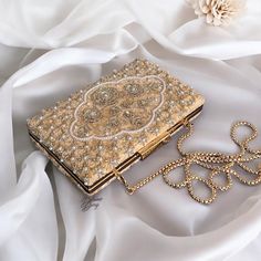 Elevate your bridal ensemble with our exquisite Ivory Bridal Clutch adorned with intricate bead and Zardozi work on one side of the clutch. Crafted from luxurious velvet, this clutch exudes elegance and sophistication. The soft suede lining ensures your essentials are safely tucked away, while the thick chain adds a touch of glamour. Perfect for completing your dreamy bridal look with finesse and style. In a market flooded with cheap imitations, our commitment to using premium materials and meti Festive Gold Hand Embellished Clutch, Festive Gold Hand-embellished Clutch, Elegant Embroidered Bridal Accessories For Wedding, Elegant Embroidered Wedding Bridal Accessories, Gold Clutch With Zari Work For Wedding, Gold Wedding Clutch With Zari Work, Gold Hand Embellished Clutch For Wedding, Gold Beaded Clutch For Wedding, Gold Embellished Clutch For Receptions