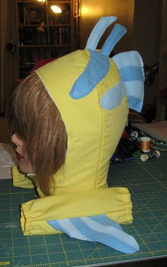 a person wearing a yellow and blue costume on top of a cutting board with scissors