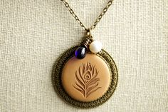 An artistic depiction of a peacock feather engraved into a wooden cabochon has been set on a bronze base in this handmade necklace that has been created with a glass teardrop wrapped by hand in bronze wire, and a fresh water pearl charm. Full pendant length is approximately 1.4 inches (36mm). This necklace comes with a matching bronze chain. If you would like a length of chain different than offered, please contact me for pricing. There are also matching earrings! http://etsy.me/2vqiCxq See more Bohemian Necklace With Peacock Design For Gifts, Vintage Jewelry With Peacock Design As Gift, Unique Brass Teardrop Necklaces, Vintage Jewelry With Peacock Design For Gift, Antique Jewelry With Peacock Design For Gifts, Antique Peacock Design Jewelry As A Gift, Vintage Peacock Design Jewelry As Gift, Bohemian Teardrop Brass Necklace, Bohemian Peacock Necklace As Gift