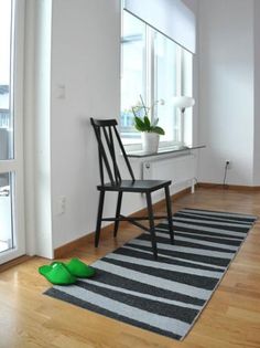 a black chair sitting on top of a wooden floor next to a white window sill