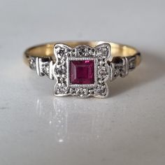 Art deco 18CT, platinum panel ring with Ruby and diamonds. Beautiful princess cut ruby 3.5mm surrounded by eight diamonds. The ornate setting of platinum panel, the design that is so indicative of the 1920's, leading into the shoulders the design continues with a single diamond on each side. Size- UK- M US- 6.5 Hallmark- 18CT&PLAT (18CT gold and platinum) The item will be packaged in a leatherette ring box using royal mail special delivery. All of my pieces are offsite in secure storage and will Art Deco Ruby Ring With Diamond Details, Vintage Red Diamond Ring With Halo Setting, Red Victorian Diamond Ring, Vintage Ruby Ring With Diamond Accents, Art Deco Ruby Ring For Formal Occasions, Art Deco Ruby Gemstone Rings, Red Art Deco Ring With Center Stone, Vintage Ruby Rings With Diamond Accents, Art Deco Ruby Diamond Ring