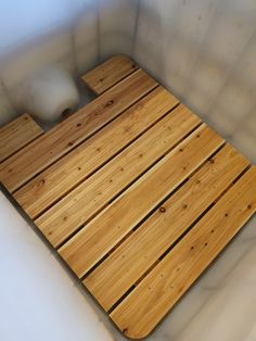 a wooden floor in the corner of a room with white walls and wood planks