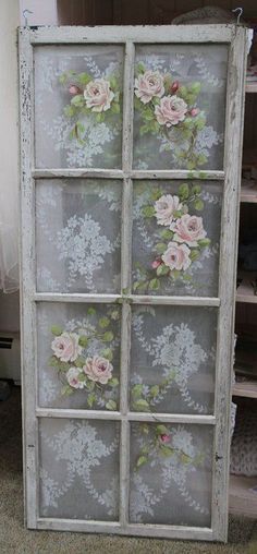 an old window with flowers painted on the glass is sitting in front of a shelf