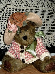 a brown teddy bear wearing a pink and white sweater with a rose on it's head