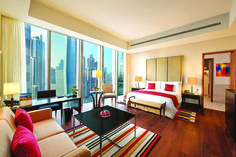 a hotel room with a bed, couch and desk in front of a large window