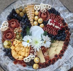 a platter filled with cheese, crackers, berries and other foods on top of a lace covered table cloth