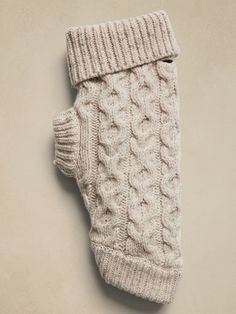 a white knitted mitten laying on top of a beige wall with the bottom part off