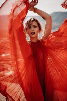 a woman in an orange dress with her hands on her head