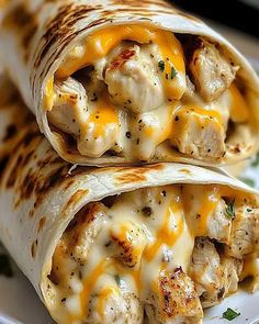 two chicken burritos on a plate with cheese