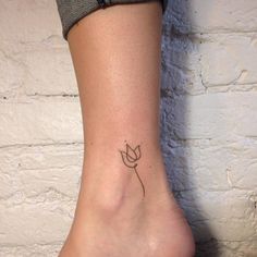 a woman's foot with a small tattoo on the side of her leg, which has an outline of a cat