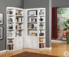 a living room with white bookcases and pictures on the wall