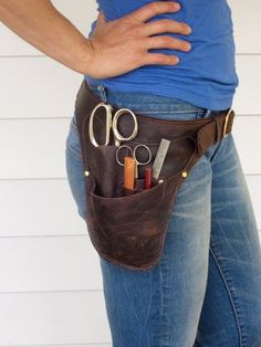 a woman wearing a leather belt with scissors and pencils in it's pocket