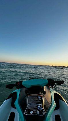 the back end of a jet ski in the ocean at sunset or sunrise, looking out to sea