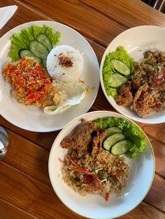 three plates filled with different types of food on top of a wooden table next to silverware