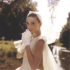 a woman in a wedding dress holding a white glove on her left hand and looking at the camera