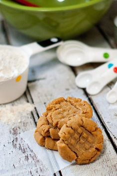 two cookies sitting on top of a wooden table next to measuring spoons and bowls