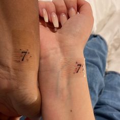 two people are holding hands with tattoos on their wrists and one has the number seven