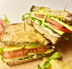 a cut in half sandwich sitting on top of a cutting board next to a tomato