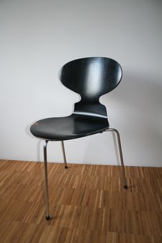 a black chair sitting on top of a hard wood floor next to a white wall