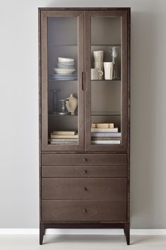 a wooden cabinet with glass doors and shelves filled with plates, bowls and cups on top