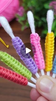 a person holding five crocheted toothbrushes in their hand, with the needle pointed at them