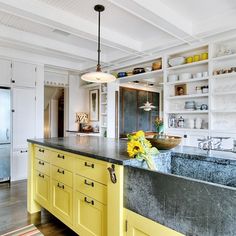 a kitchen with yellow cabinets and an island in front of a refrigerator freezer that has sunflowers on it