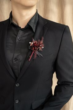 a man in a black suit with a red boutonniere on his lapel