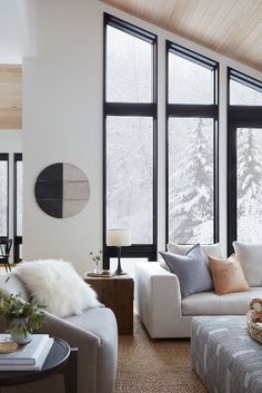 a living room filled with lots of furniture and large windows covered in wintery snow