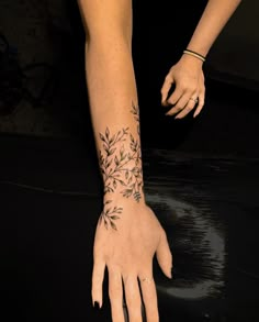 a woman's hand with a tattoo on her left wrist and the palm of her right hand