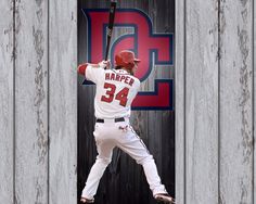 a baseball player holding a bat in front of a wooden wall with the number 24 on it